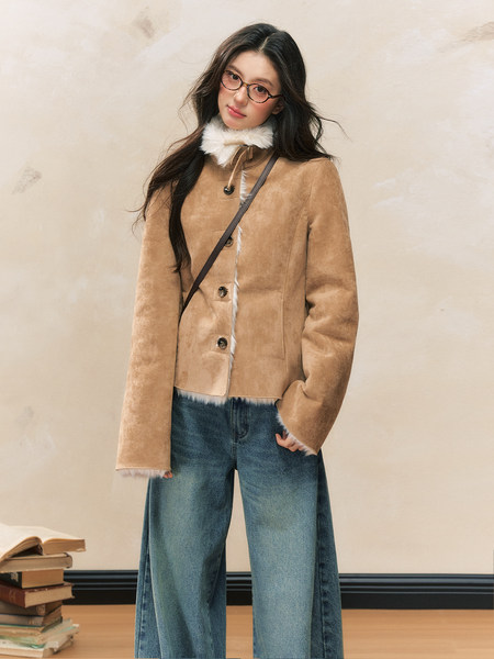 Model wearing a tan shearling-style jacket with white fur trim and blue jeans