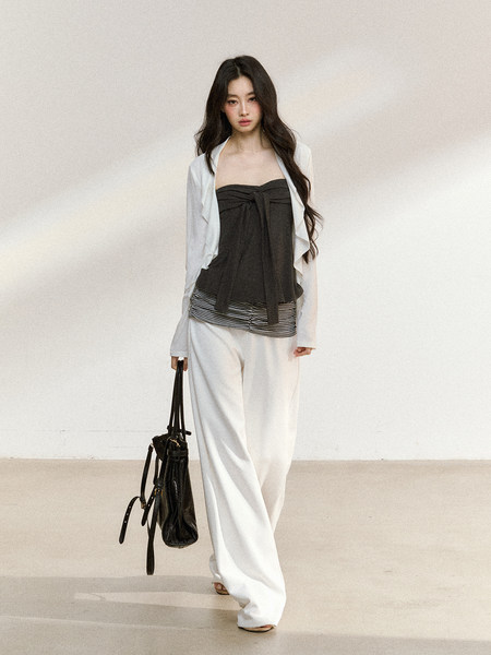 Woman modeling a layered black and white fashion outfit with wide-leg pants and a handbag