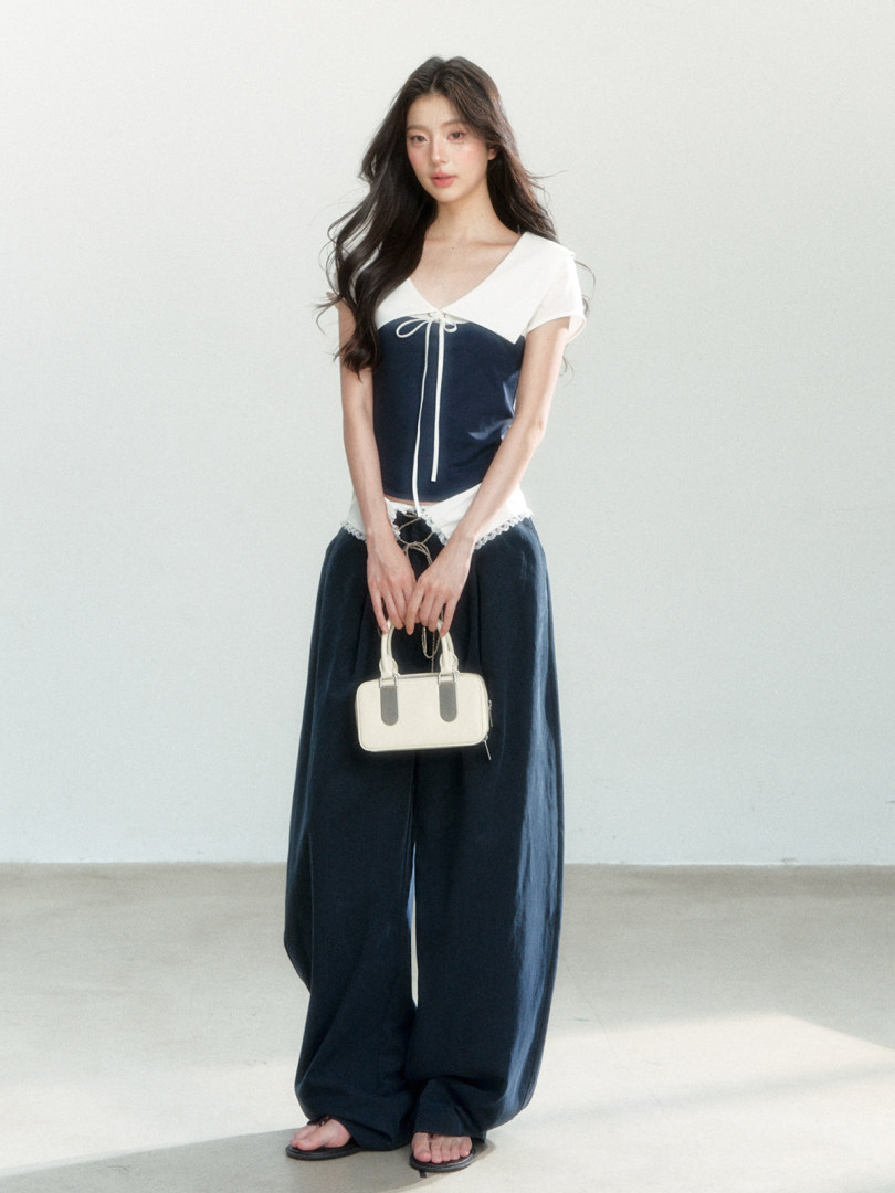 Model wearing a navy and white outfit with a small cream handbag
