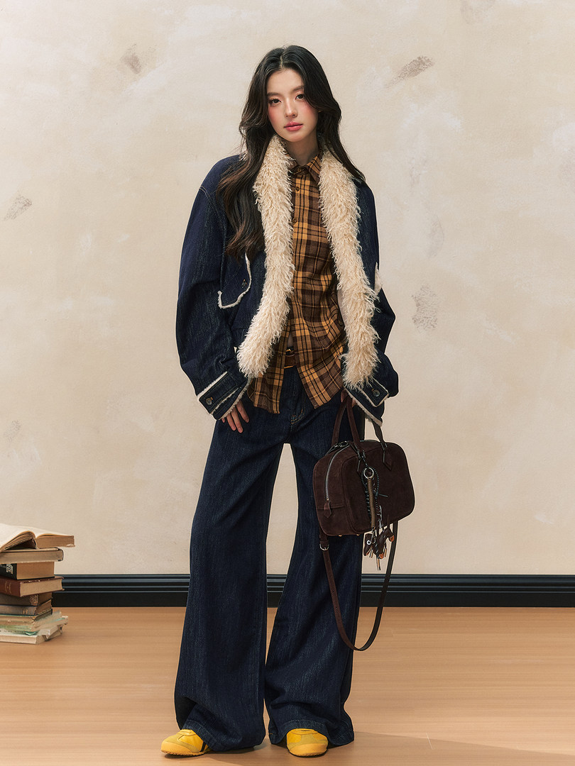 Fashion model wearing a shearling-lined denim jacket with plaid shirt, wide-leg jeans, and a handbag