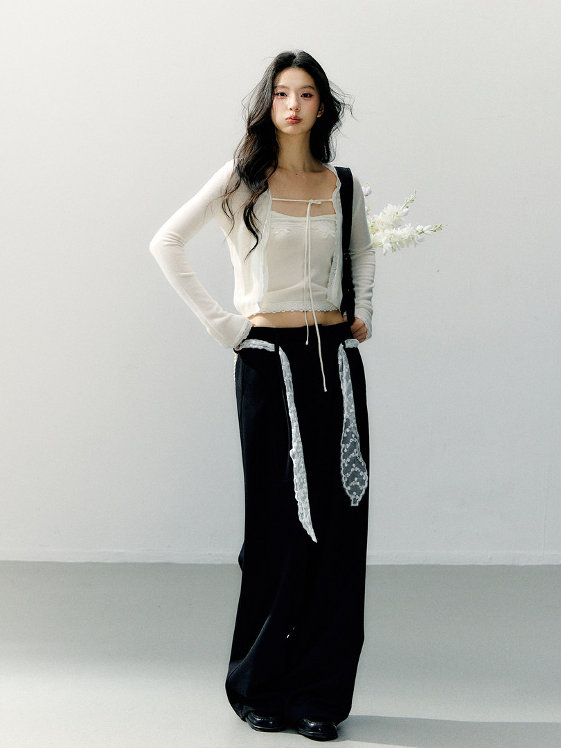 Model wearing a white lace-trim top and black wide-leg pants