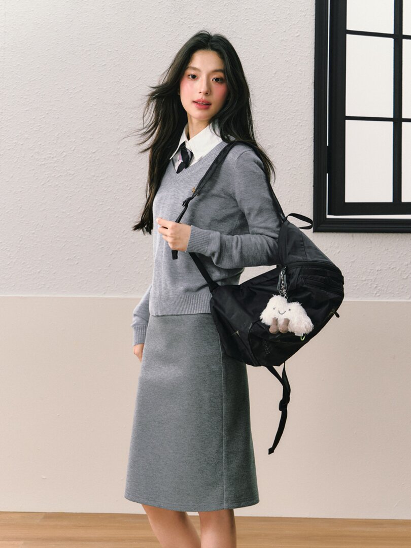 Woman wearing a gray sweater and skirt with a black backpack