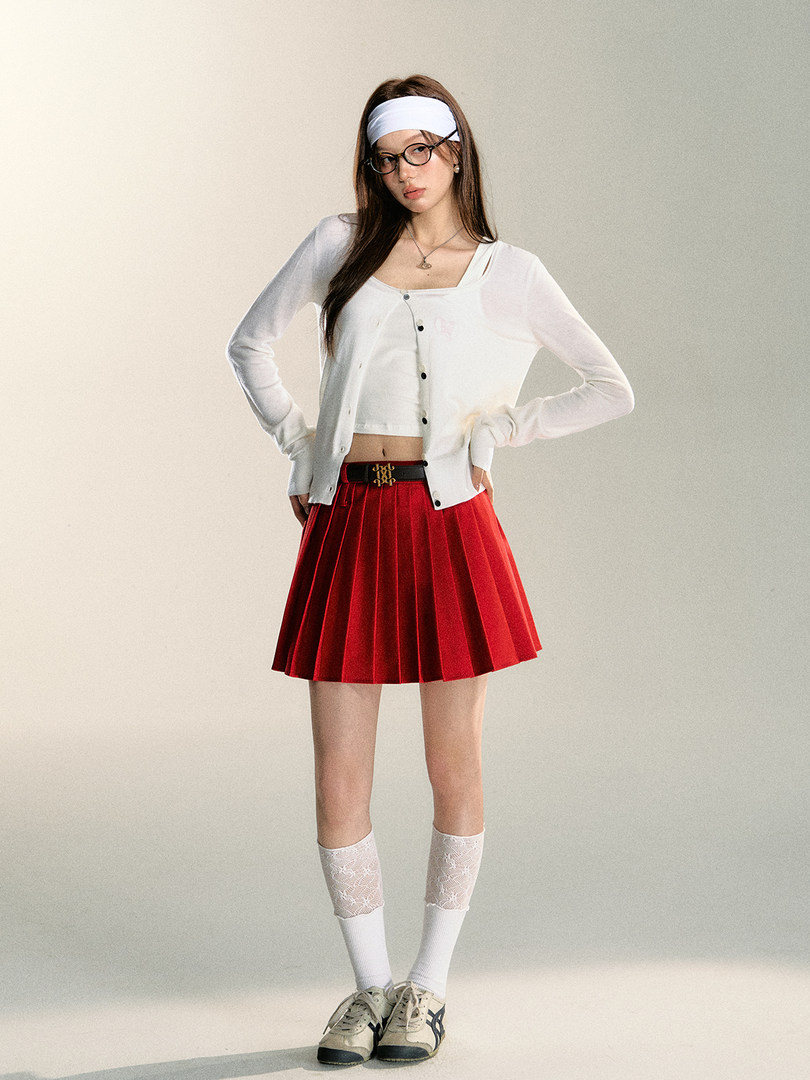 Model wearing a red pleated mini skirt with a white cardigan and sneakers