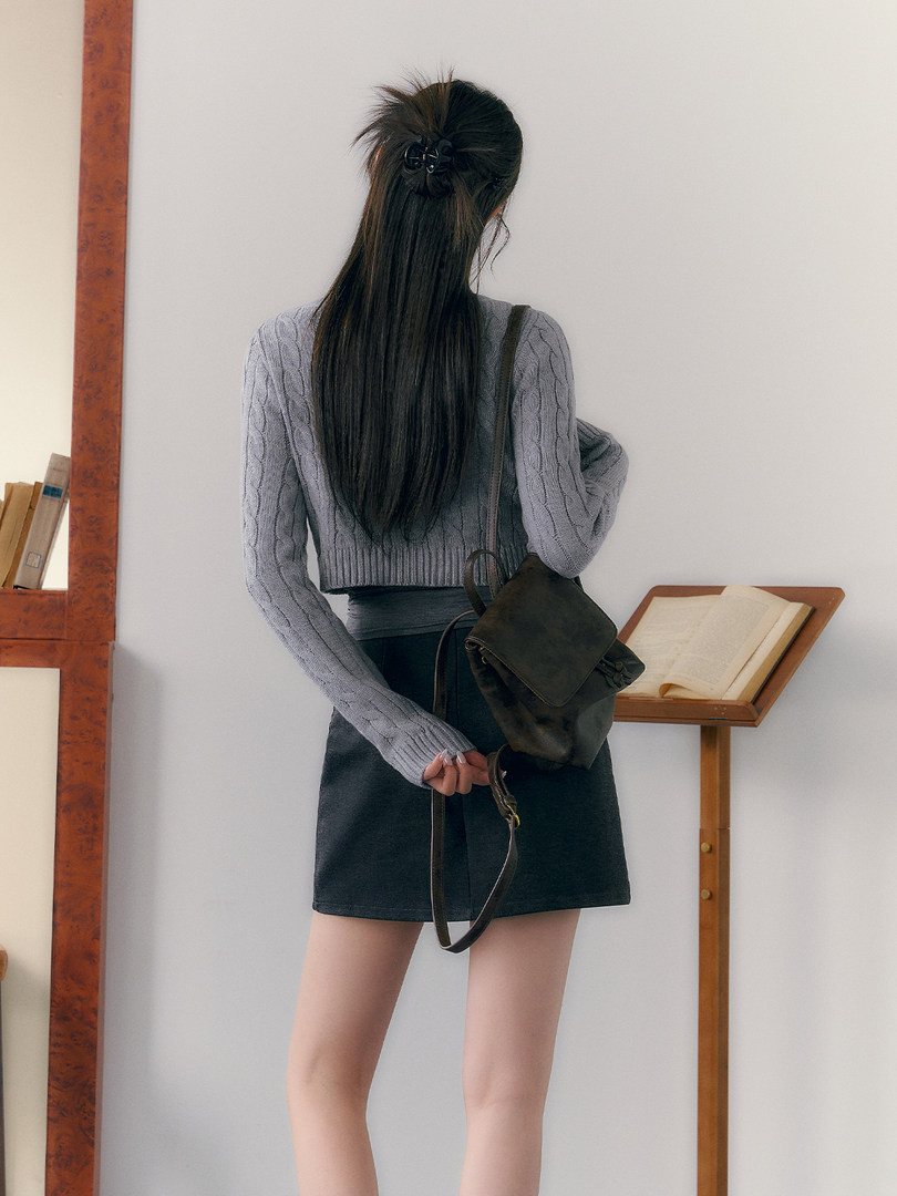 Woman wearing a gray knit sweater with a black skirt and backpack