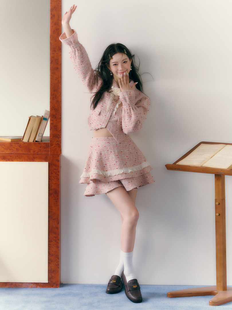 Model wearing a pink tweed two-piece outfit with a cropped jacket and mini skirt