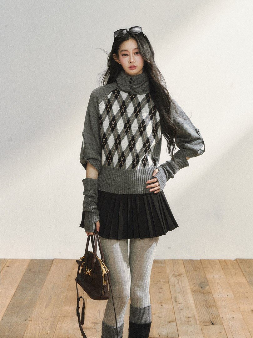 Model wearing a gray argyle knit sweater with pleated skirt and tights