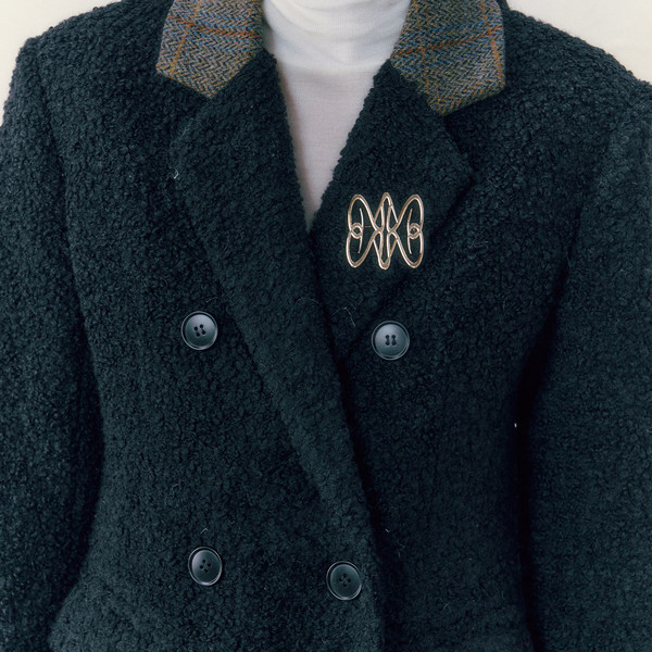 Black textured double-breasted coat worn over a white turtleneck