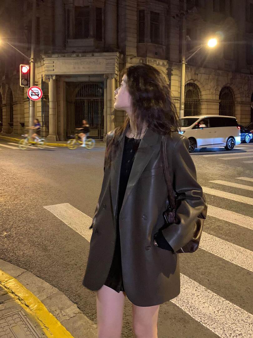 Woman wearing an oversized black blazer jacket on a city street at night