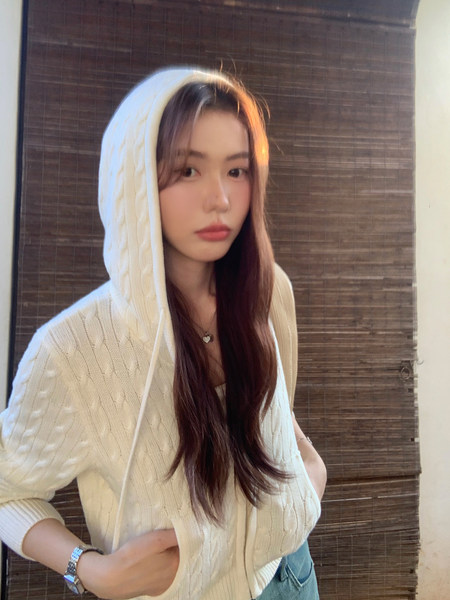Woman wearing a white cable-knit hooded sweater