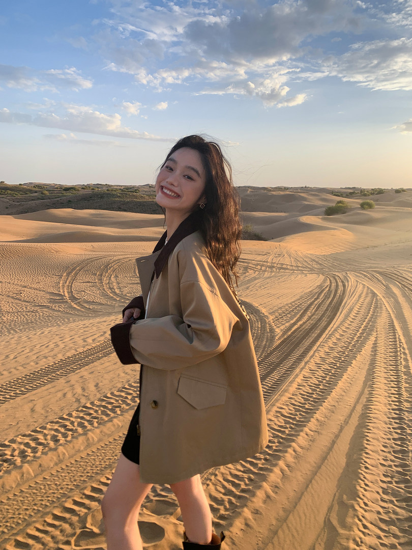 Woman wearing a beige oversized jacket in a desert landscape