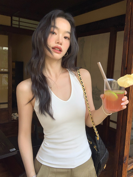 Woman wearing a white sleeveless fitted top with a black shoulder bag