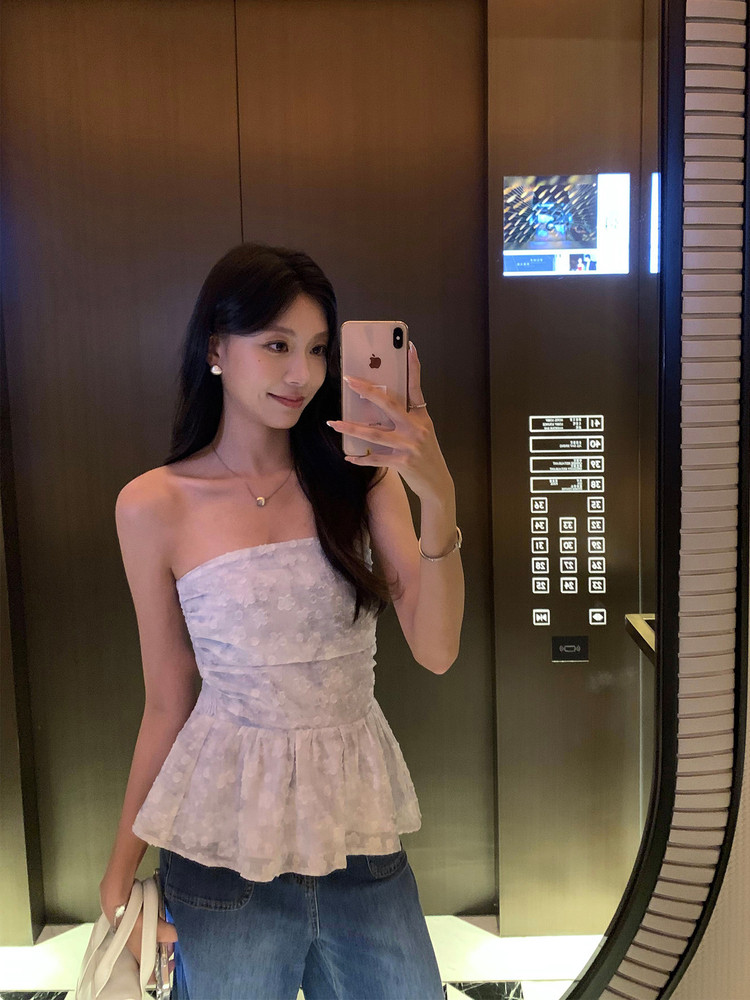Woman wearing a strapless light floral peplum top with jeans in a mirror selfie