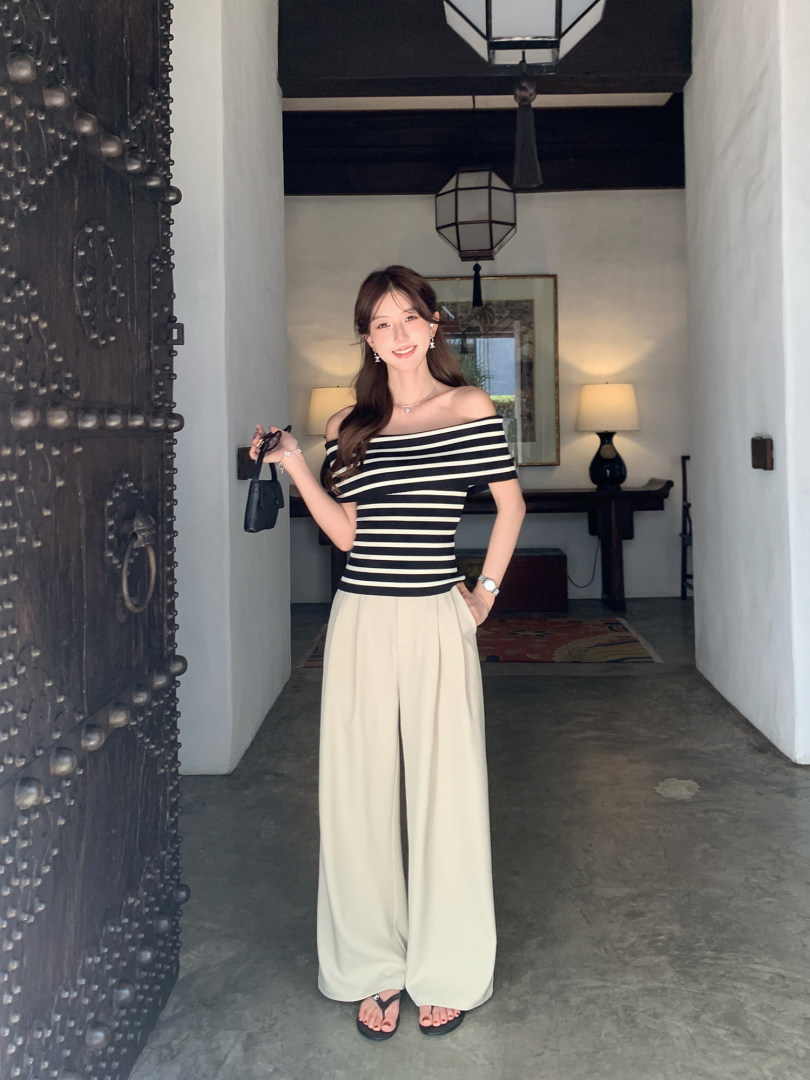 Woman wearing a black-and-cream striped off-shoulder top with cream wide-leg pants