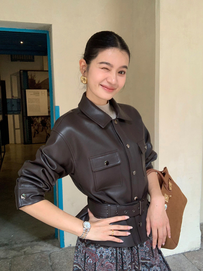 Woman wearing a dark brown belted faux leather jacket