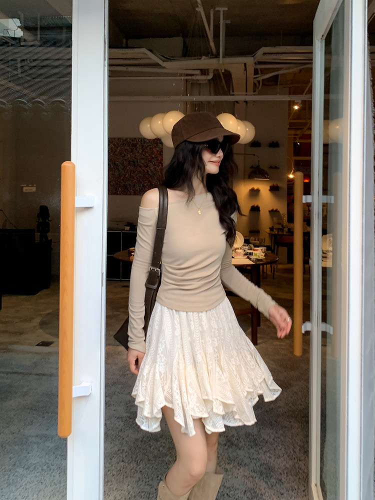 Woman wearing a beige off-shoulder top with a cream lace skirt and brown cap