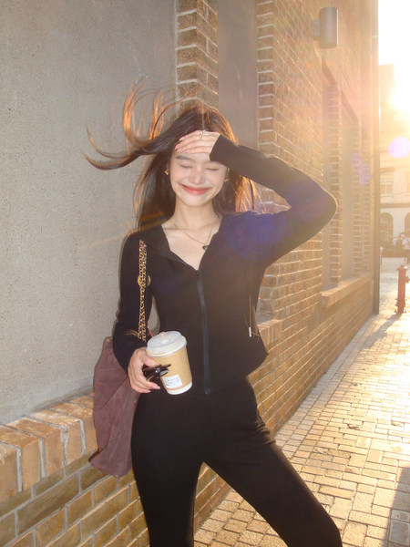 Black fitted zip-front long-sleeve outfit worn by a woman outdoors