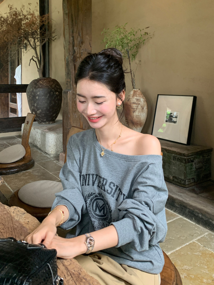 Woman wearing a gray off-shoulder university sweatshirt