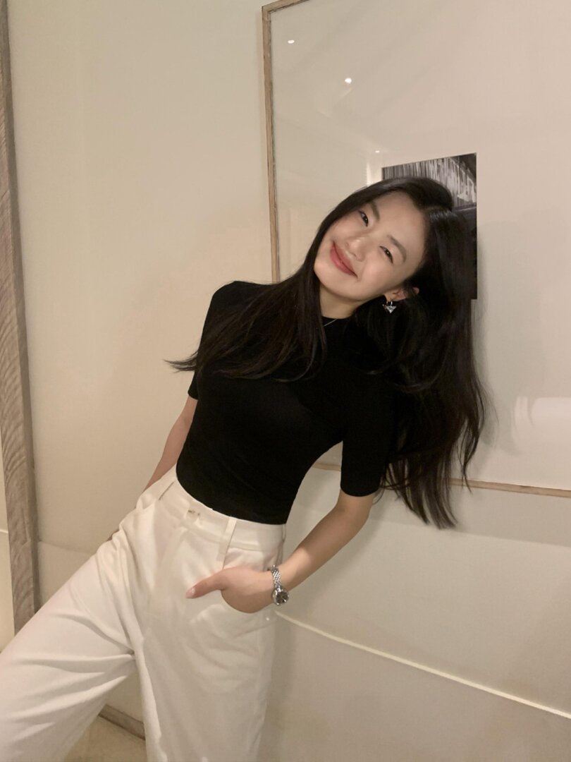 Woman wearing a black fitted top with white trousers