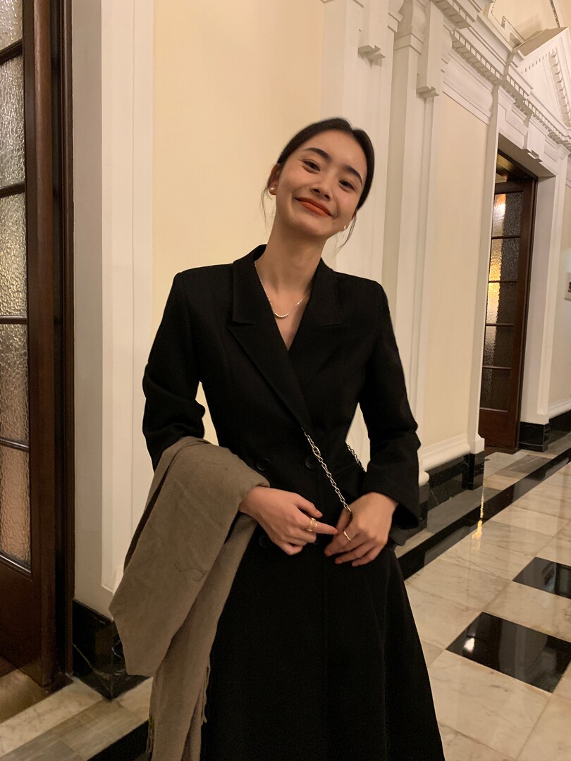 Woman wearing a black tailored long coat or blazer in an elegant indoor setting