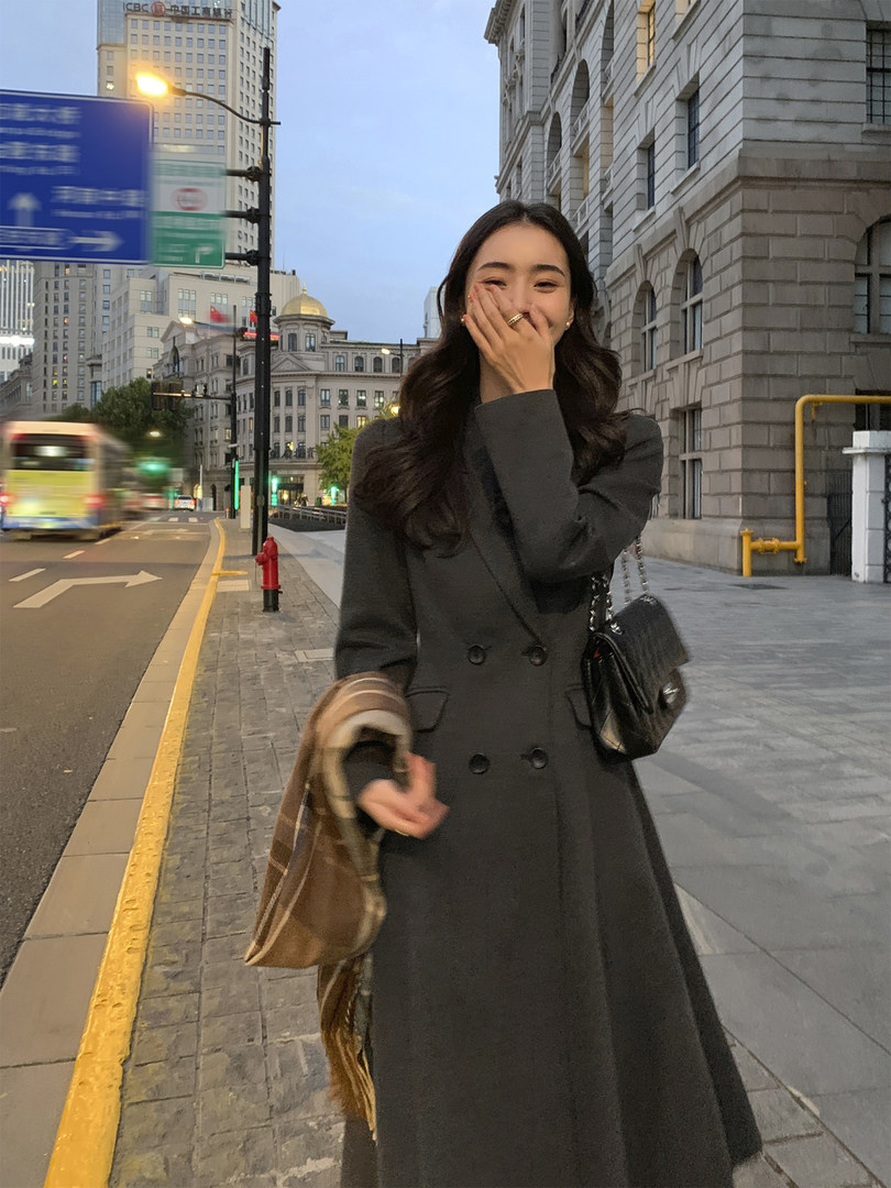 Woman wearing a dark long double-breasted coat on a city street