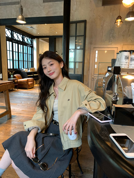 Woman wearing a beige casual jacket over a dark skirt in a cafe