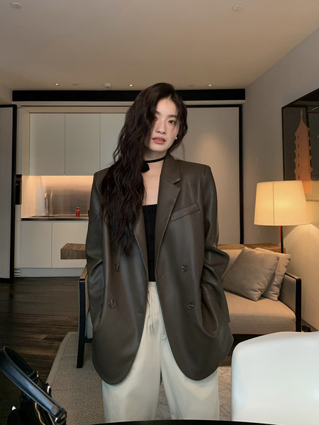 Woman wearing an oversized dark leather blazer with cream trousers