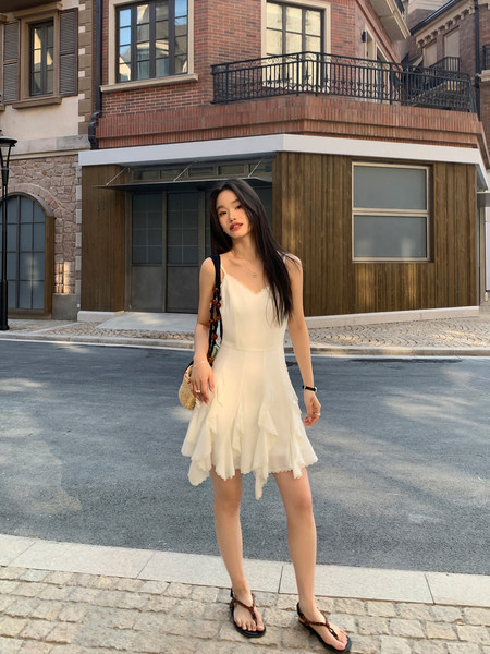 Woman wearing a cream sleeveless ruffled dress outdoors