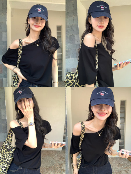 Woman modeling a black off-shoulder top with a leopard-print shoulder bag and navy cap