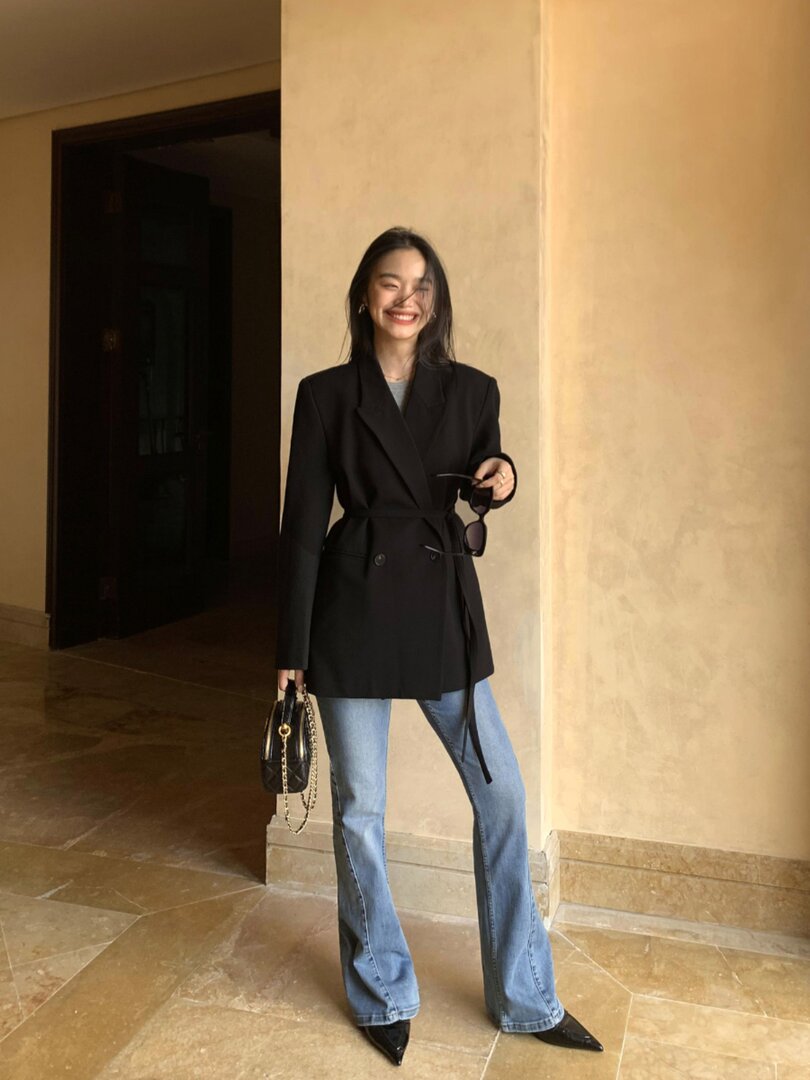 Woman wearing a black blazer with light blue jeans and black heels