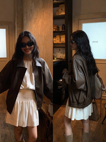 Model wearing a dark leather jacket over a white dress and boots