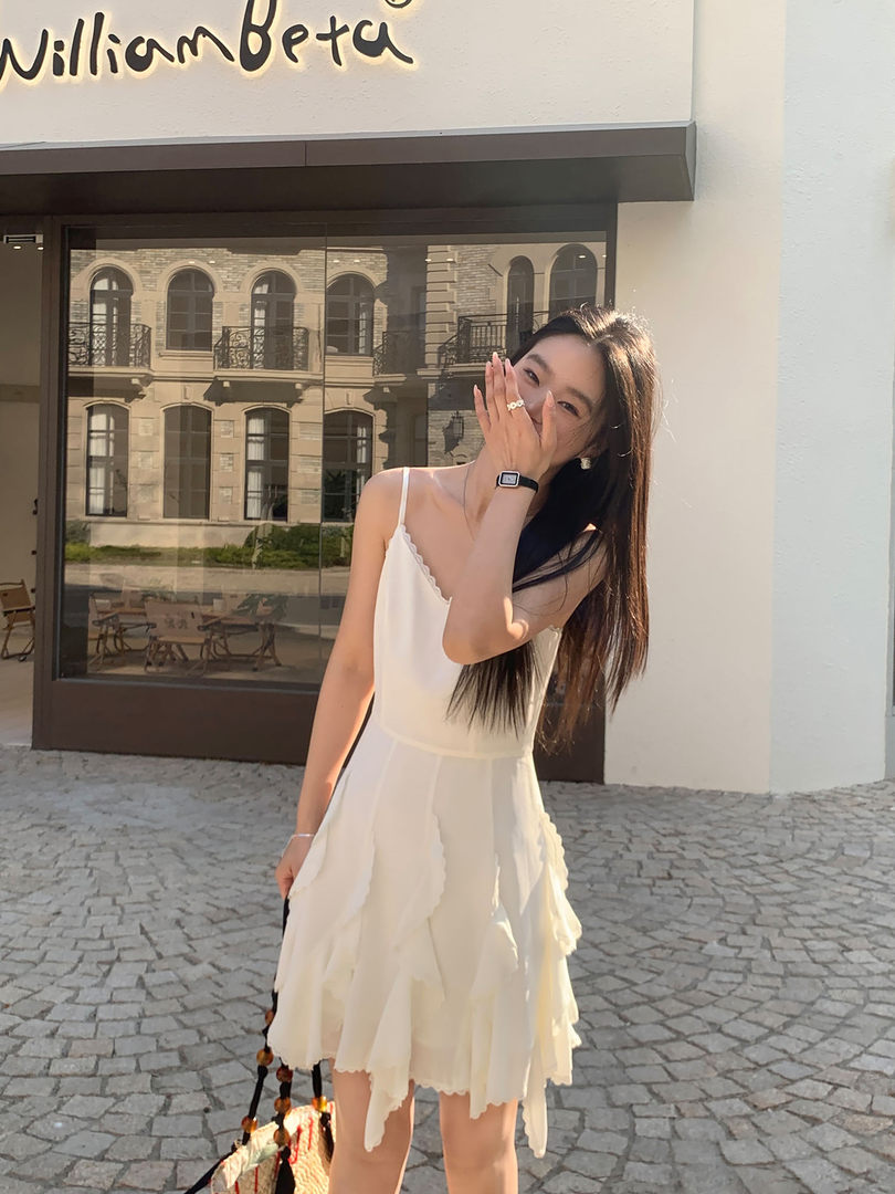 Woman wearing a cream spaghetti-strap ruffle dress outdoors