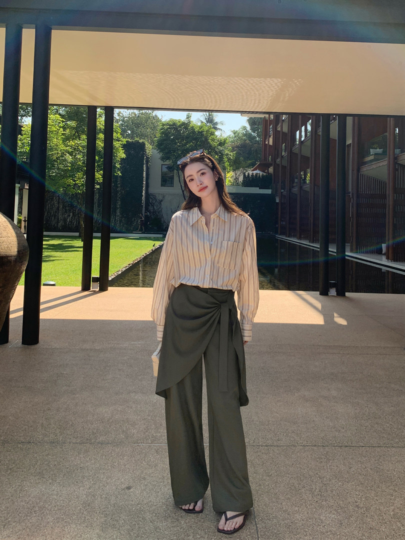 Woman wearing a striped button-up shirt and wide-leg dark pants outdoors