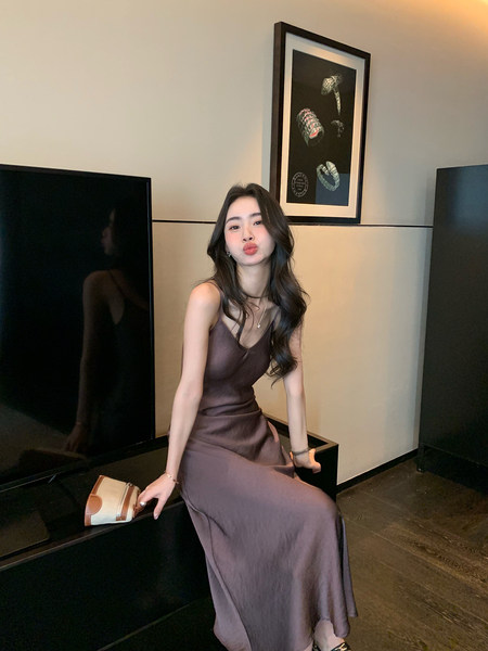 Woman wearing a brown satin slip dress posing indoors