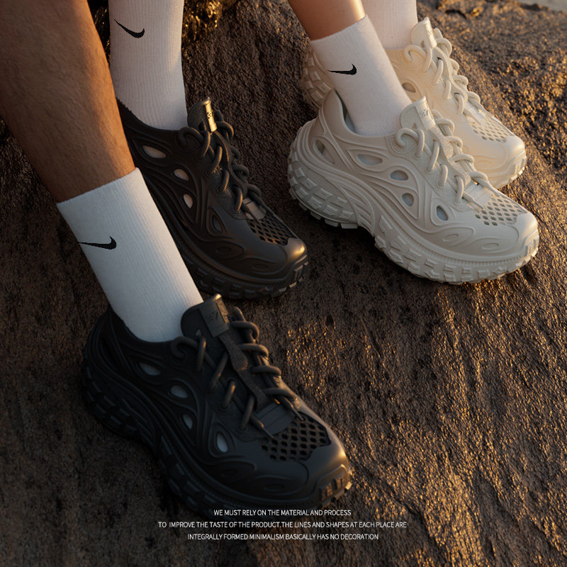 Chunky futuristic sneakers worn with white socks on rocky ground