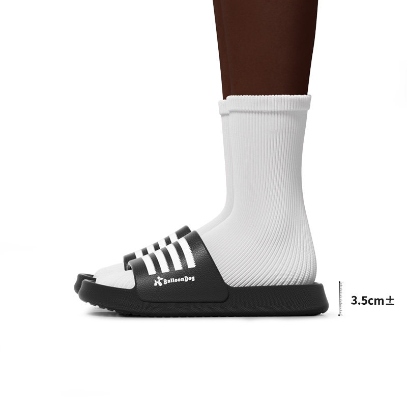 Black slide sandal worn with a white sock on a model foot