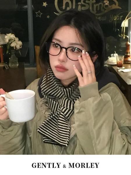 Woman wearing a striped scarf and glasses with an olive jacket