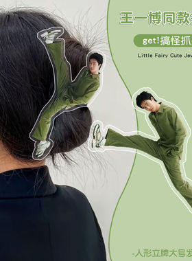 Wang Yibo stands up and grabs the back of his head, while t