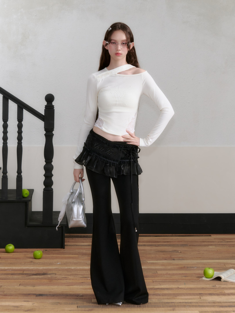 Model wearing a white asymmetrical long-sleeve top with black flared pants and a silver handbag