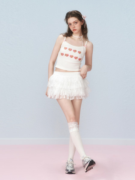 Model wearing a white heart-print crop top with a ruffled mini skirt and platform sneakers