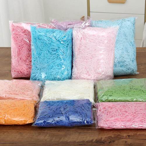 gift lined with shredded paper filling colored packing box