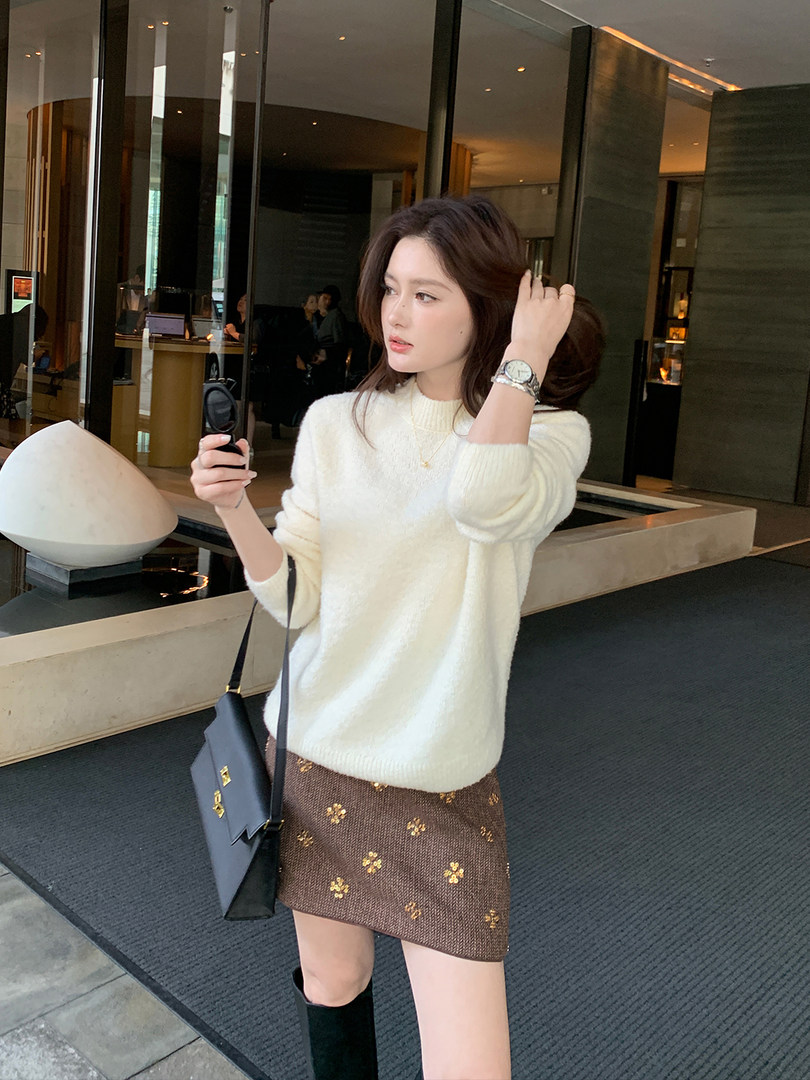 Woman wearing a white fuzzy sweater with a brown patterned mini skirt and black boots