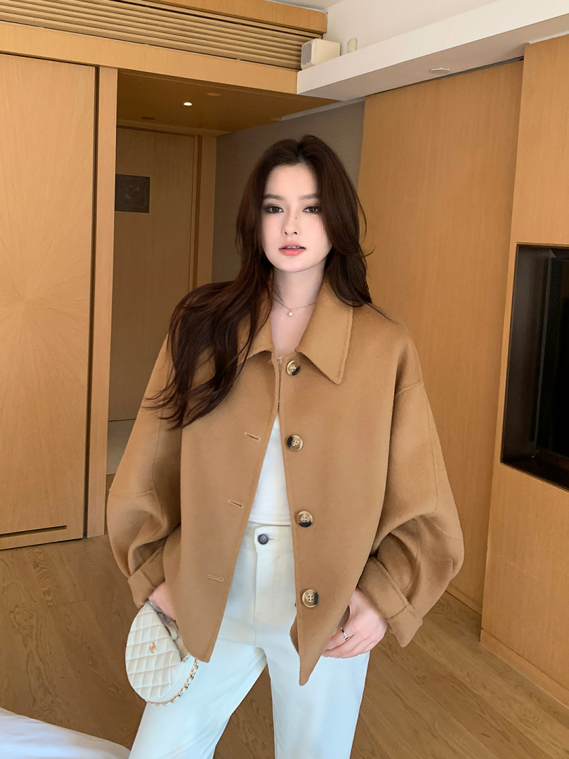 Camel oversized button-up jacket worn with white pants in an indoor fashion photo