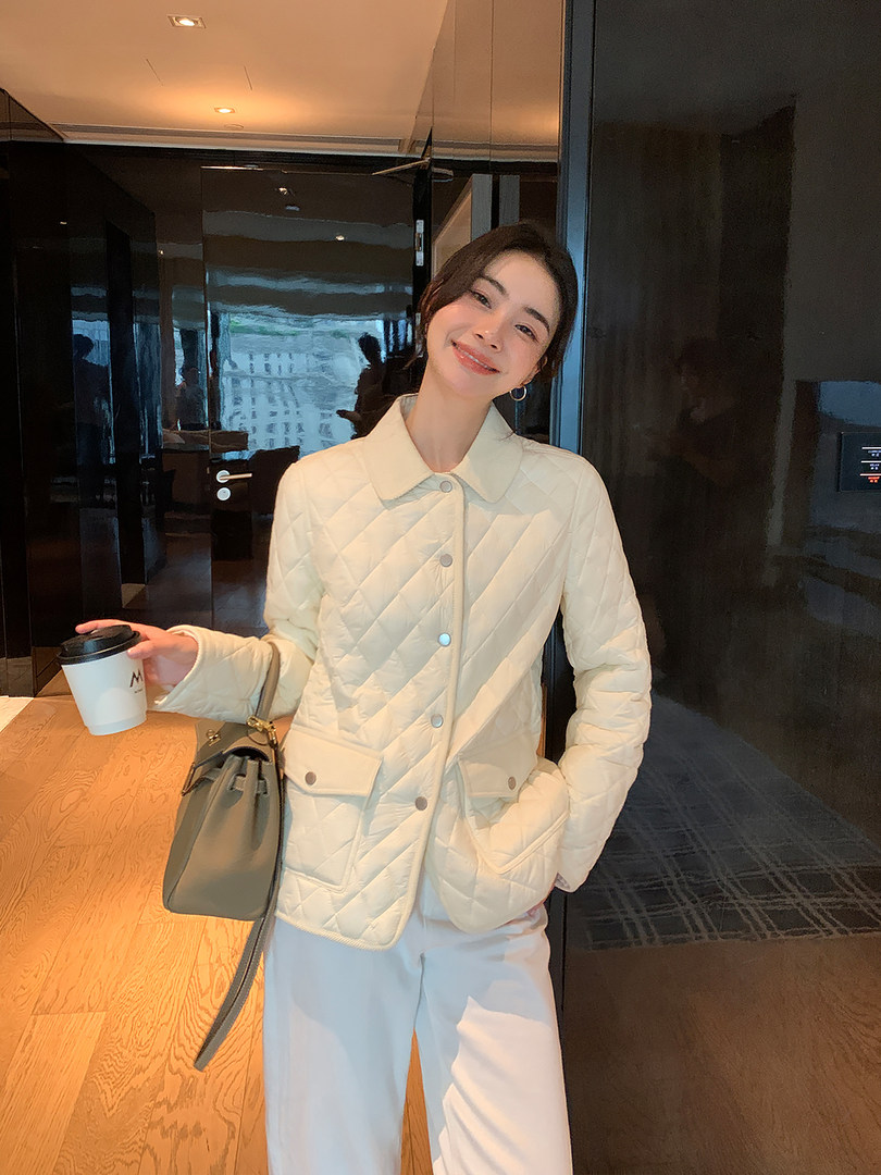 Woman wearing a cream quilted jacket with a gray handbag