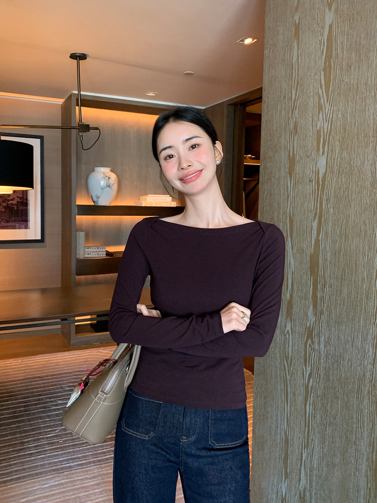 Woman wearing a fitted dark long-sleeve top with jeans and a handbag