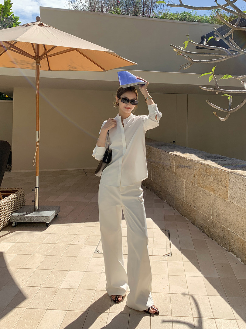 Woman wearing a white minimalist blouse and wide-leg trousers outdoors