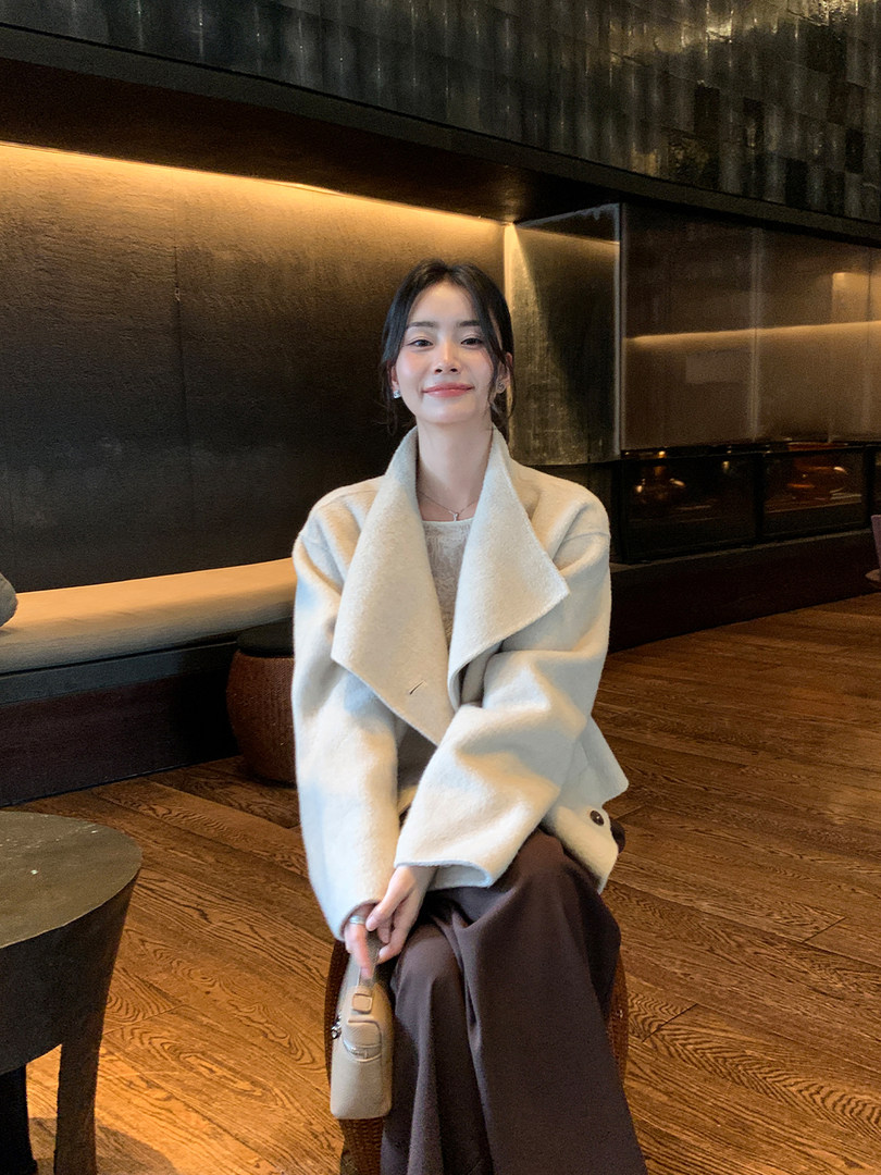 Woman wearing a light cream coat in an indoor setting