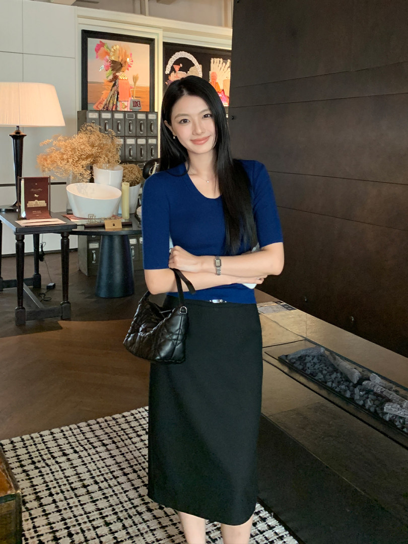 Woman wearing a blue fitted top and black skirt with a black handbag