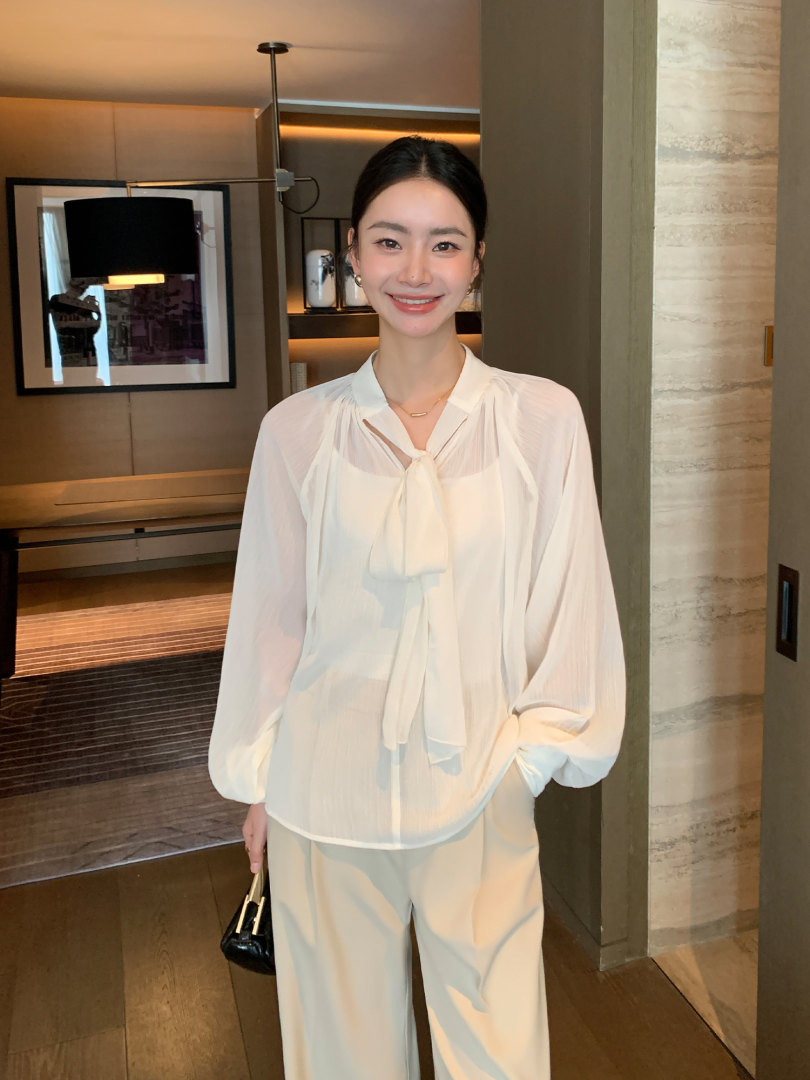 Woman wearing a white sheer blouse with matching wide-leg trousers