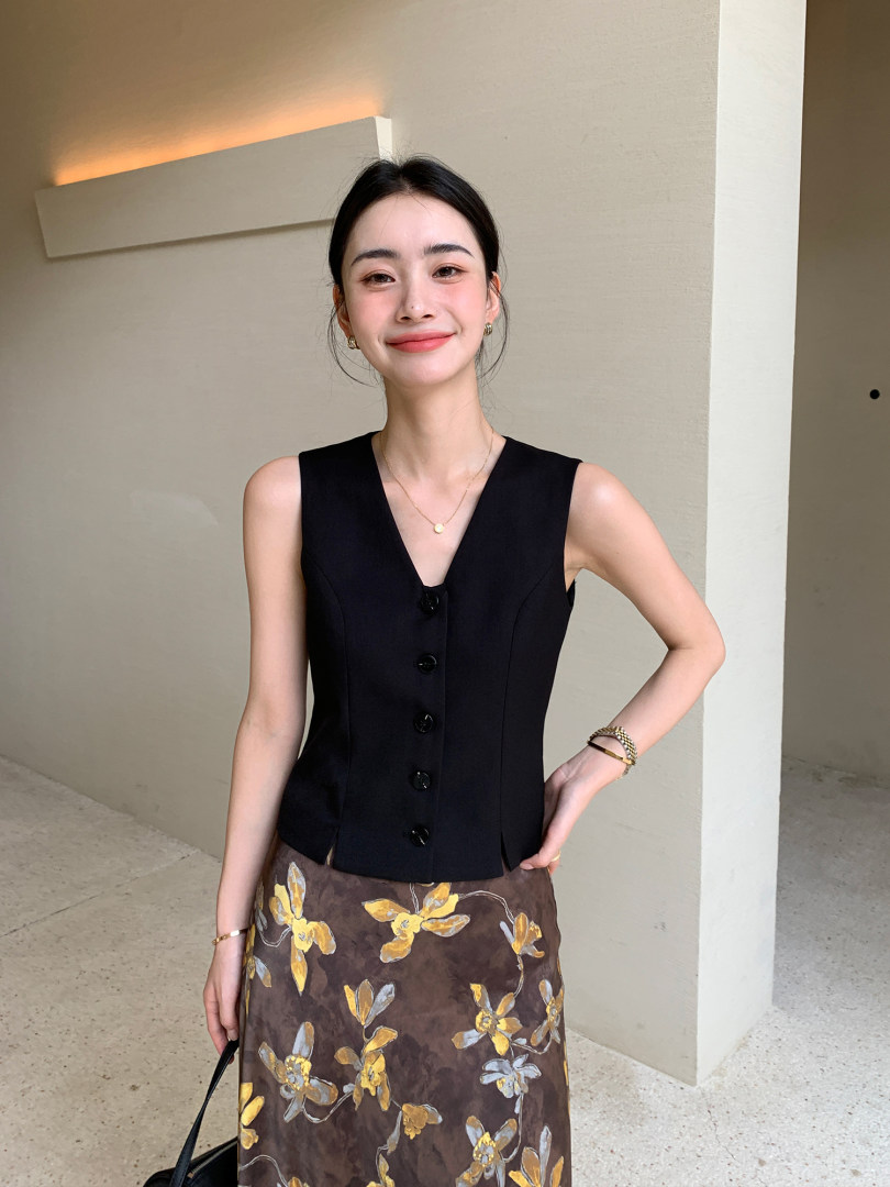 Woman wearing a black sleeveless button-front vest top with a floral skirt