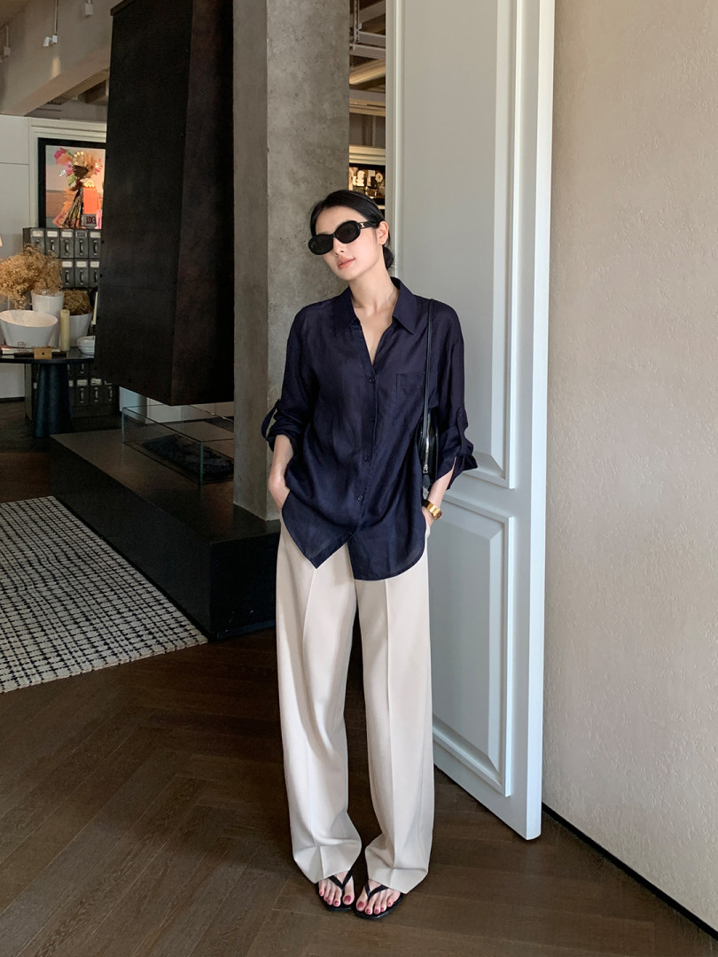 Model wearing a navy button-up shirt with beige wide-leg trousers